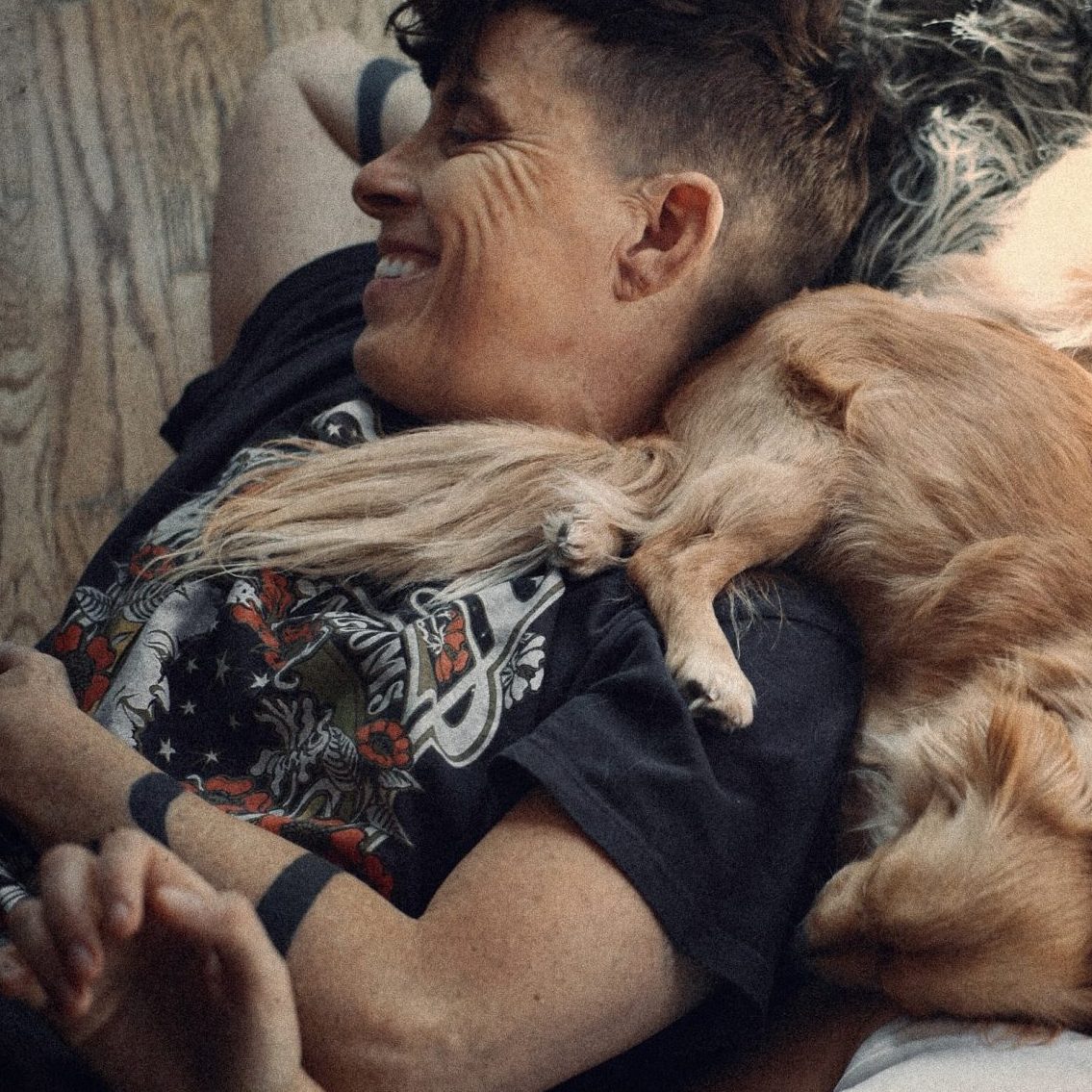 Two people lying on the floor laughing, surrounded by dogs