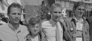 Black-and-white photo of student demonstrators standing in a line with their arms around each other's shoulders.