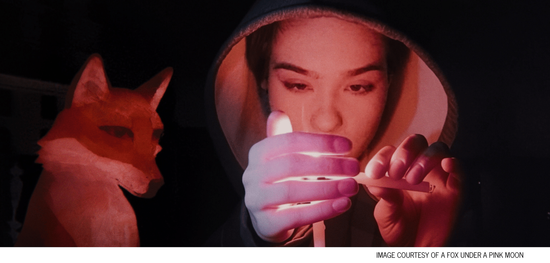 A girl shields a candle flame with her hand as an animated fox looks on