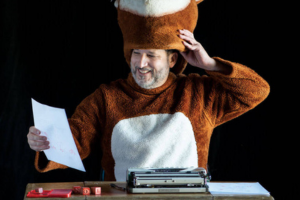 Chris Vitiello in fox suit, seated at typewriter