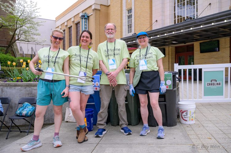 Green Team members in matching green shirts pose outside of the theater